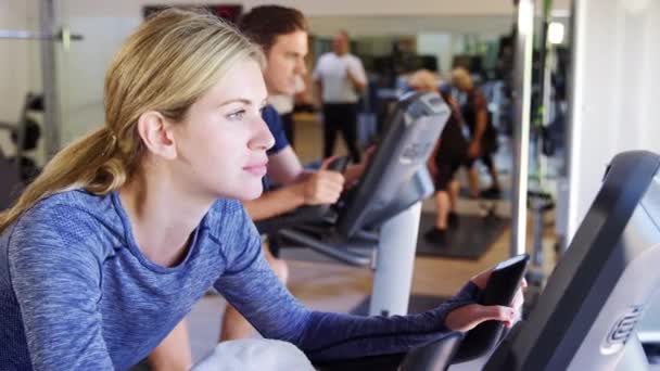 Spor Salonunda Bisiklet Makineleri Üzerinde Egzersiz Yapan Kadın Erkek Video — Stok video