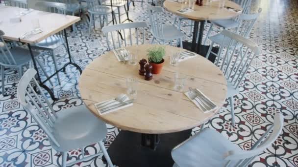 在空荡荡的餐厅餐厅里 有高耸的手持式视野 集中在一张圆形的木桌上 有位置设置和椅子 — 图库视频影像