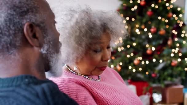 慢动作视频的高级非洲裔美国夫妇坐在沙发上的圣诞树和谈话 — 图库视频影像