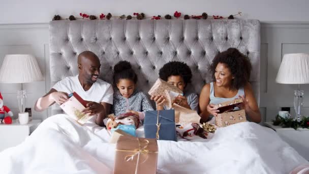 快乐的孩子与父母在床上的视频在圣诞节早晨开幕礼物 — 图库视频影像