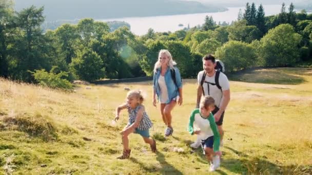 Famiglia Sorridente Che Indossa Zaini Arrampicata Collina Escursione Attraverso Lake — Video Stock