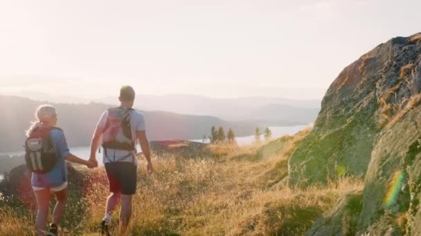 在屋湖区徒步时穿着背包爬山的情侣后景停下来看美丽的风景 慢镜头拍摄 — 图库视频影像
