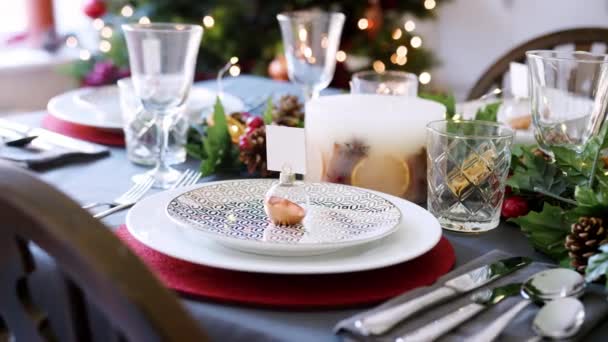 安物の宝石名刺ホルダー プレートと緑と赤い季節装飾 細部のアレンジお祝いクリスマスのダイニング テーブル — ストック動画