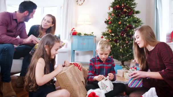 当一家人一起庆祝圣诞节时 兴奋的孩子们坐在地板上打开礼物 慢镜头 — 图库视频影像