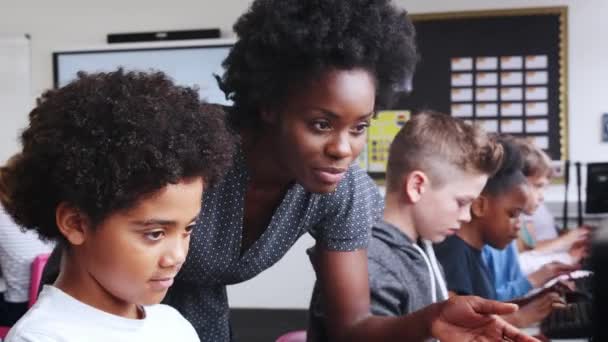 女教师拿着数字平板电脑 Ict 班的电脑上工作的学生系列帮助男生录像 — 图库视频影像