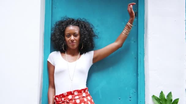 カメラを戸口に傾いて赤水玉ズボンを身に着けているファッショナブルな若い黒人女性 — ストック動画
