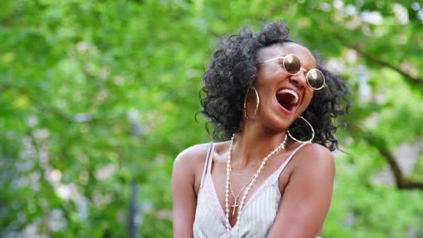 穿着圆形太阳镜和迷你裙的时髦年轻黑人妇女在户外玩耍和大笑 — 图库视频影像