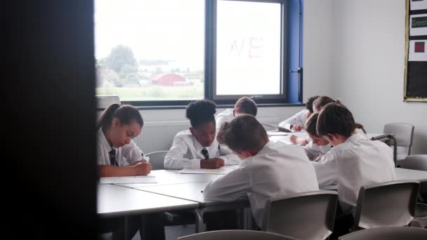 一群身穿制服的高中生坐在教室里的课桌前 在练习本上写字 用慢动作视频拍摄 — 图库视频影像