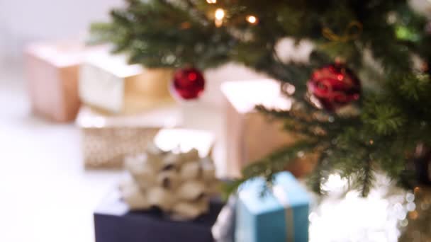 赤のつまらないもので飾られたクリスマス ツリーの下で整理のギフトをクローズ アップ ラック フォーカス — ストック動画