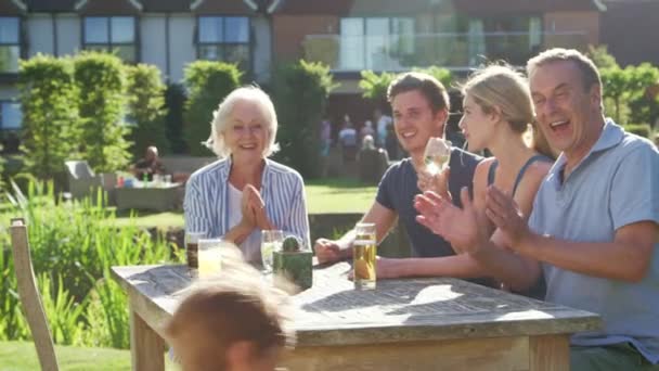 Mehrgenerationenfamilie Genießt Sommerdrink Freien Garten Und Kinder Spielen Vordergrund Aufgenommen — Stockvideo
