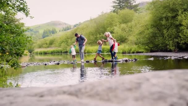飛石で英国湖水地方 スローモーションで撮影を使用して川を渡る児童両親の全長側面図 — ストック動画
