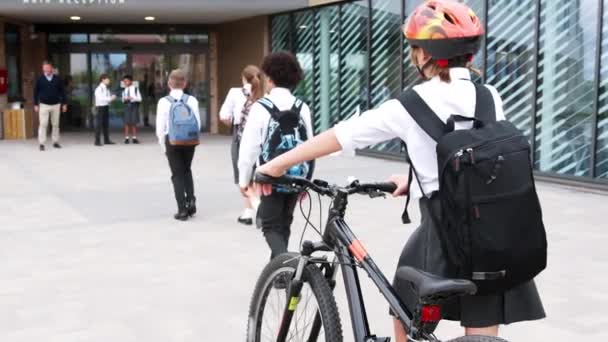 校舎外の生徒の背面図徒歩と自転車での授業のために到着する教師によって迎えられる スローモーションビデオで撮影 — ストック動画