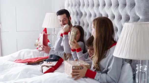 圣诞节那天 孩子和女儿的父母在家里打开礼物的兴奋家庭的床上的视频 — 图库视频影像