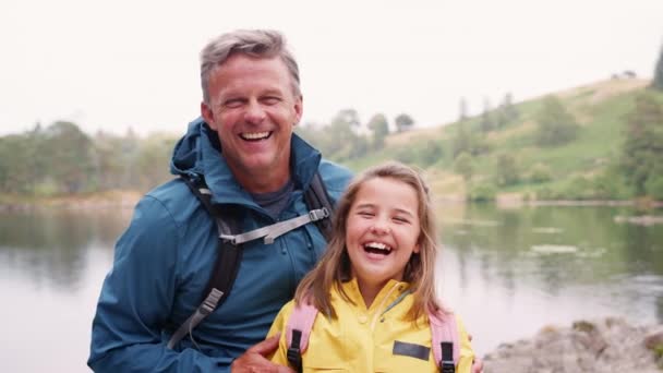年配の男性が 湖の岸で孫娘と立っているクローズ アップ 湖水地方 イギリス — ストック動画