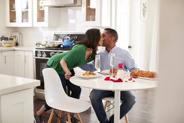中年混血女人亲吻她的伴侣后 在厨房为他提供浪漫的一餐 选择性的焦点 — 图库照片