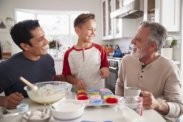 三个男性一代的家庭一起在厨房的餐桌上做蛋糕 — 图库照片
