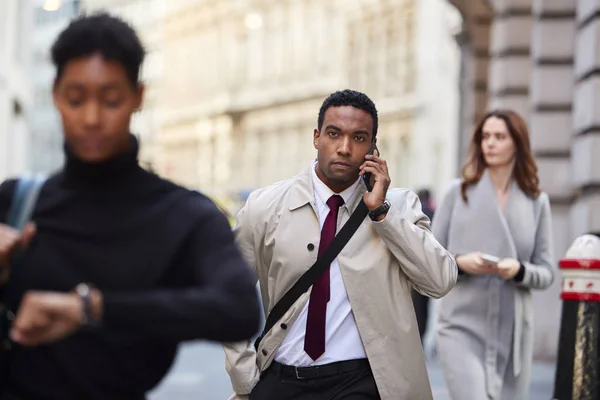 スマートフォンを使って忙しいロンドンの通りを歩くミレニアル世代の黒人ビジネスマン 選択的な焦点 — ストック写真