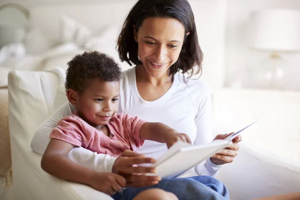 彼女の膝の上に彼女の3歳の息子と本を読んでアームチェアに座って混合人種の若い大人の母親のクローズアップ クローズアップ — ストック写真