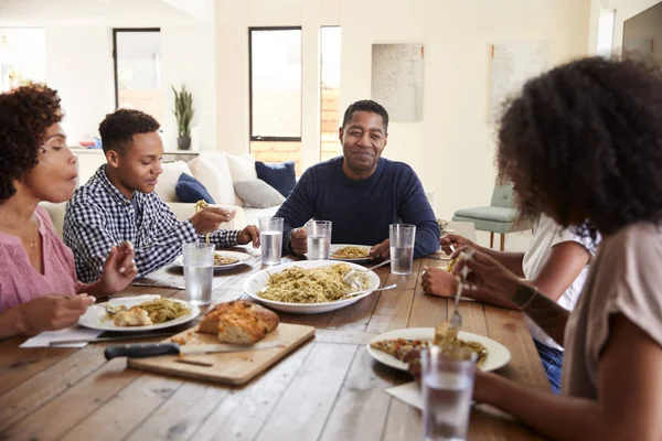 テーブルに座って妻や家族と夕食を食べている中年の黒人男性 — ストック写真