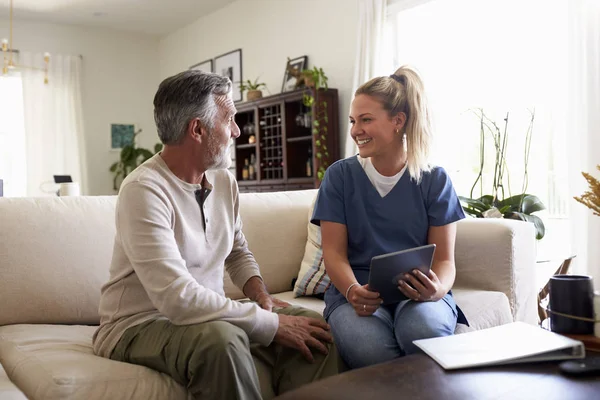 Kvinnlig Sjukvårdspersonal Använder Tablet Med Senior Hispanic Man Ett Hembesök — Stockfoto