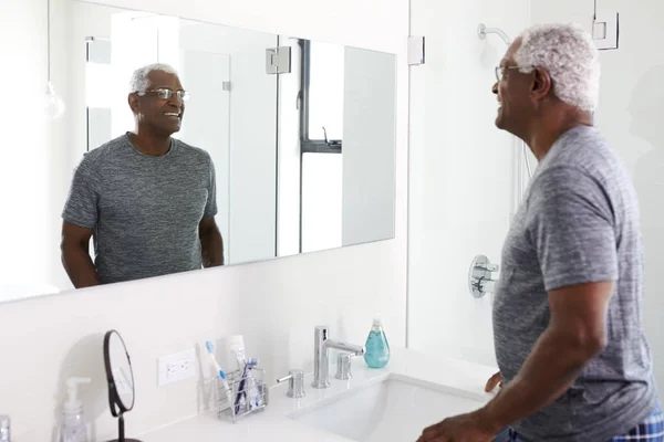 Hombre Mayor Sonriente Mirando Reflexión Espejo Baño Usando Pijamas —  Fotos de Stock