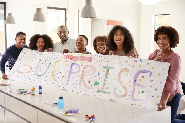 三代黑人家庭在家里举着一个惊喜派对的牌子 — 图库照片