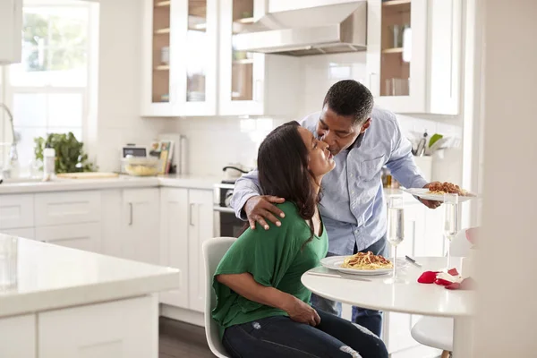 彼は彼の台所のテーブルで彼女に食事を提供するように彼のパートナーにキス男 選択的な焦点 — ストック写真