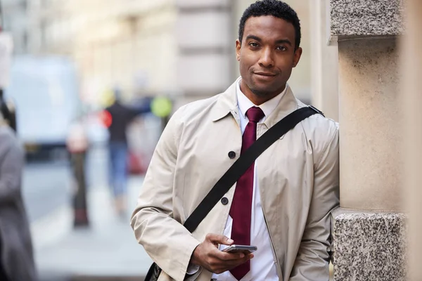 Молодой Черный Бизнесмен Опираясь Стену Улице Лондоне Держит Телефон Улыбается — стоковое фото
