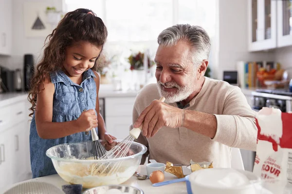 ヒスパニックの女の子と彼女のおじいちゃんは キッチンテーブルで一緒にケーキの混合物を泡立て クローズアップ — ストック写真