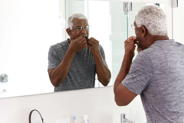 Senior Man Flossing Tanden Kijken Naar Reflectie Badkamerspiegel Dragen Pyjama — Stockfoto