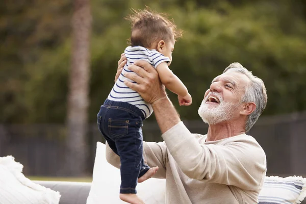 Senior Hispanic Man Sitting Garden Lifting His Baby Grandson Air — Stock Photo, Image