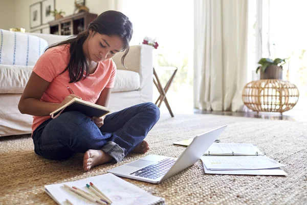 十几岁的女孩做她的家庭作业坐在地板上的客厅 低角度 — 图库照片