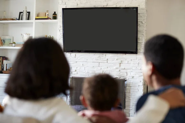 ソファに座って リビングルームで一緒にテレビを見ている若い家族のバックビュー クローズアップ テレビに焦点を当てます — ストック写真