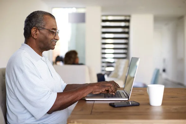Ανώτερος Μαύρος Άνθρωπος Κάθεται Στο Τραπέζι Χρησιμοποιώντας Ένα Φορητό Υπολογιστή — Φωτογραφία Αρχείου