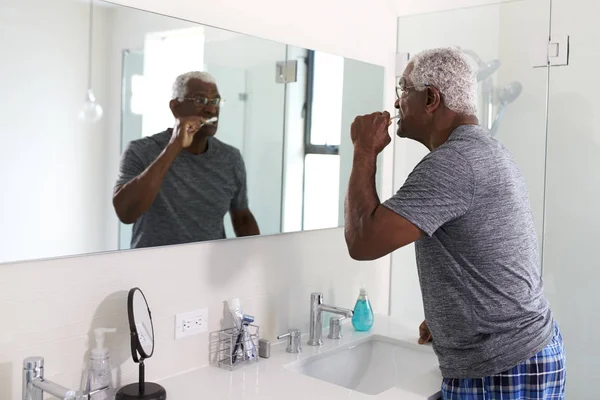 Älterer Mann Sieht Spiegelung Badezimmerspiegel Und Trägt Schlafanzug Beim Zähneputzen — Stockfoto