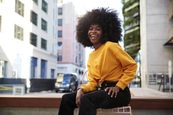Młoda Czarna Kobieta Afro Włosy Siedzi Krześle Ulicy Śmiejąc Się — Zdjęcie stockowe
