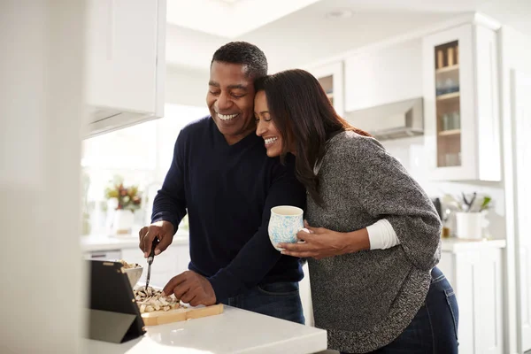 中年混血夫妇站在厨房的台面准备食物遵循平板电脑上的食谱 选择性的焦点 — 图库照片