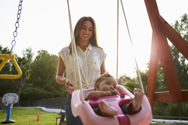 Jovem Mãe Hispânica Empurrando Seu Bebê Balanço Playground Parque Close — Fotografia de Stock