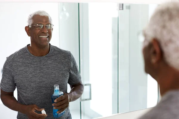 Senior Man Met Mondwash Kijken Naar Reflectie Badkamerspiegel Dragen Pyjama — Stockfoto