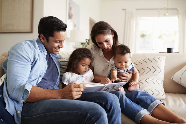 Joven Familia Hispana Cuatro Personas Sentadas Sofá Leyendo Libro Juntas — Foto de Stock