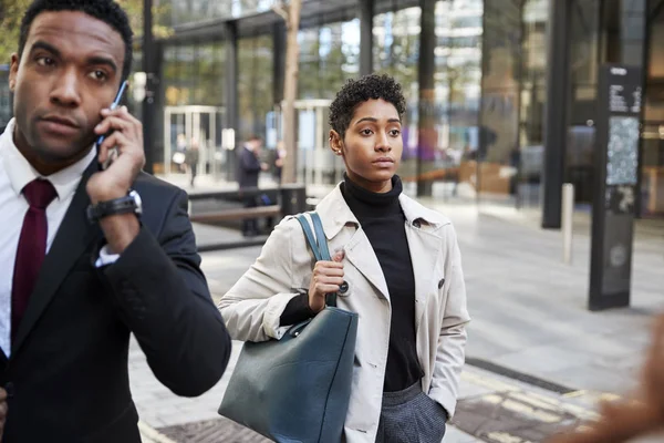 两个商人走在伦敦金融城的一条街上 男人用智能手机 女人提着一个包 有选择地集中注意力 — 图库照片