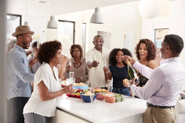 中年の黒人男性が3世代家族と一緒に自宅で祝うためにシャンパンを開く — ストック写真
