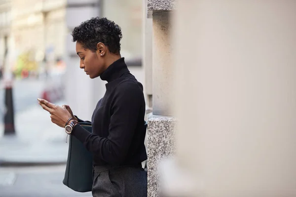 ロンドンの通りに立っている若い黒人女性彼女のスマートフォン サイドビュー クローズアップ 選択的フォーカス — ストック写真
