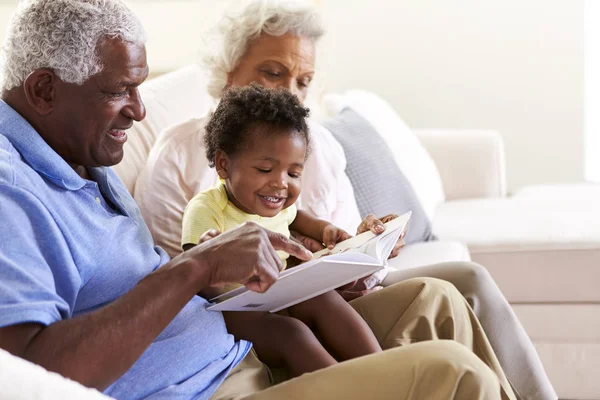 Grootouders Zittend Bank Thuis Met Baby Kleindochter Lezen Boek Samen — Stockfoto