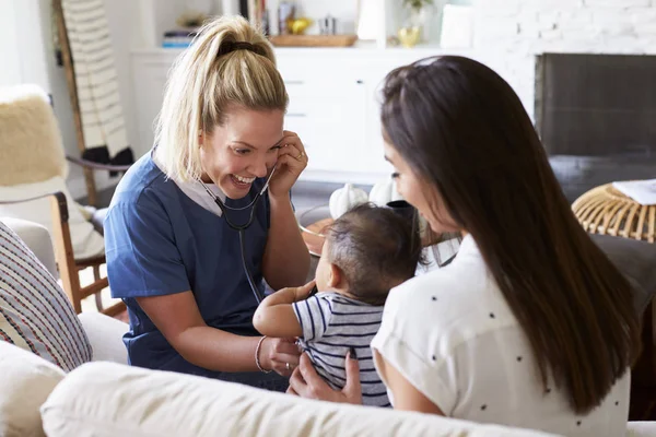 Женщина Медицинский Работник Навещает Молодую Маму Ребенка Дома Используя Стетоскоп — стоковое фото