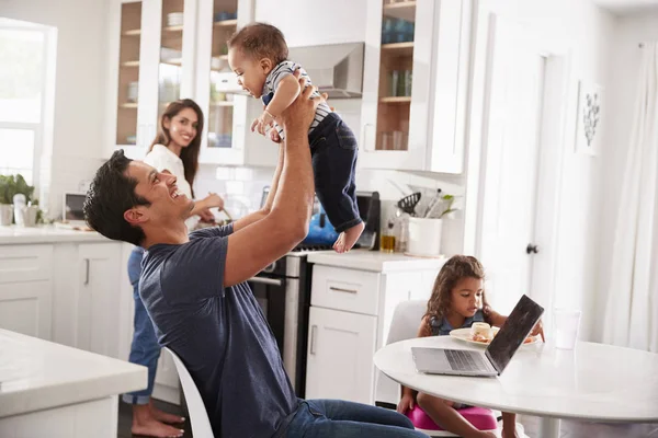 Joven Familia Hispana Cocina Papá Levantando Bebé Aire Mamá Cocinando —  Fotos de Stock