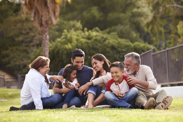 Feliz Familia Hispana Tres Generaciones Sentados Césped Juntos Parque Enfoque —  Fotos de Stock