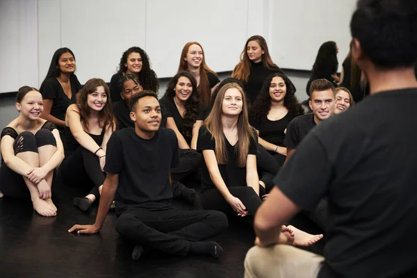舞台芸術学校の先生がリハーサルスタジオで床に座っている生徒と話す — ストック写真