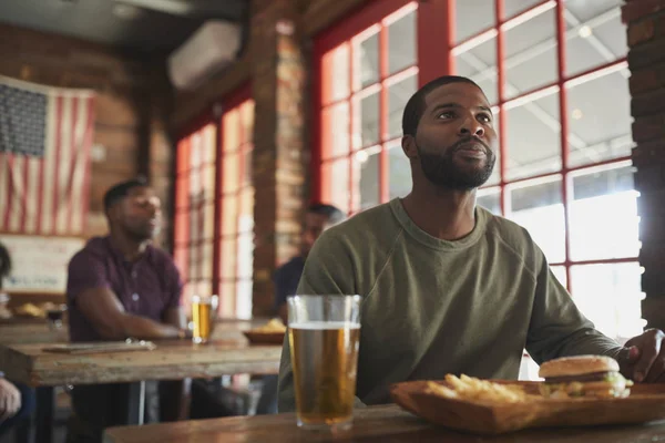 Man Tittar Spel Skärmen Sports Bar Äta Hamburgare Och Pommes — Stockfoto