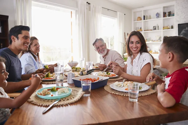 夕食を食べながらテーブルに座っている3世代のヒスパニック系家族 — ストック写真
